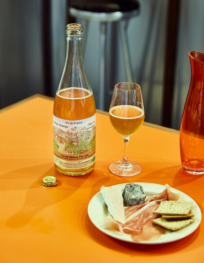 A bottle of orange wine and cheese board at Oranj